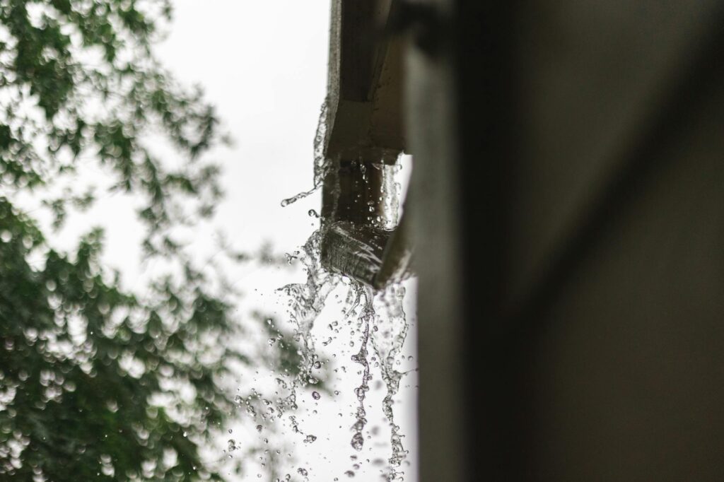 Close-up of rainwater pouring from a gutter, captured during a rainfall in Houston.